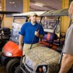 Employee talking to customer inside golf cart store.