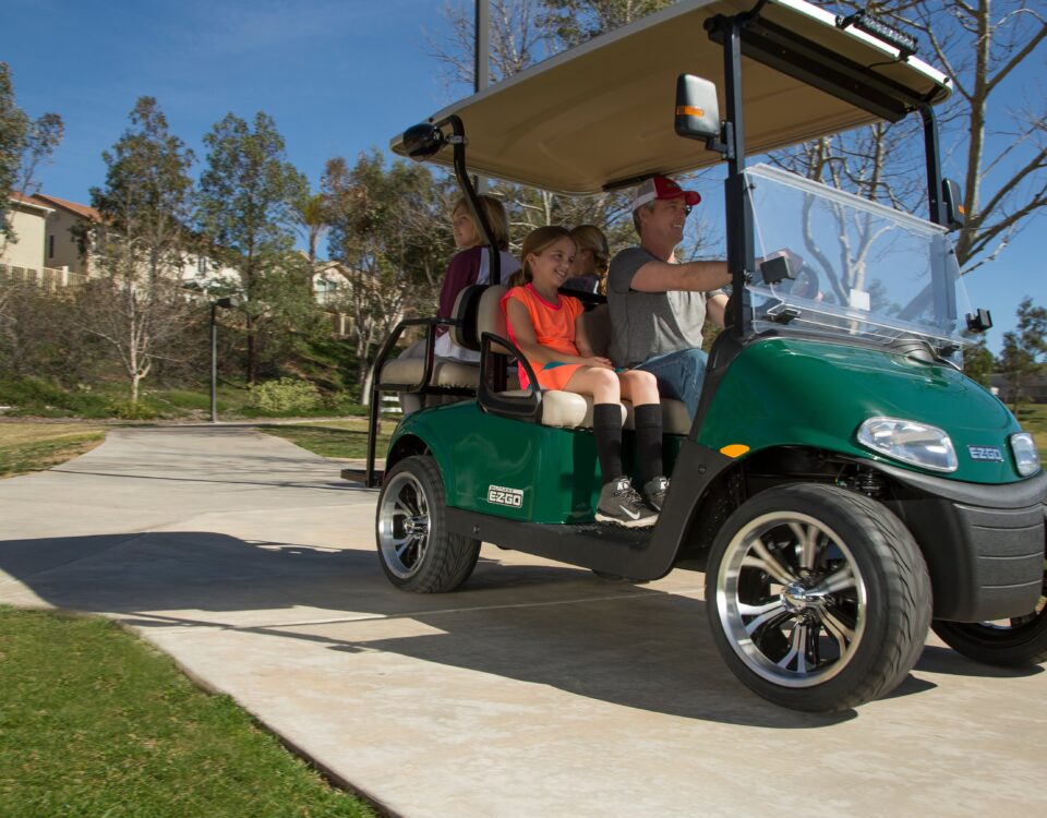 Family riding golf cart in neighborhood.