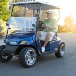 Senior couple riding cart in road.