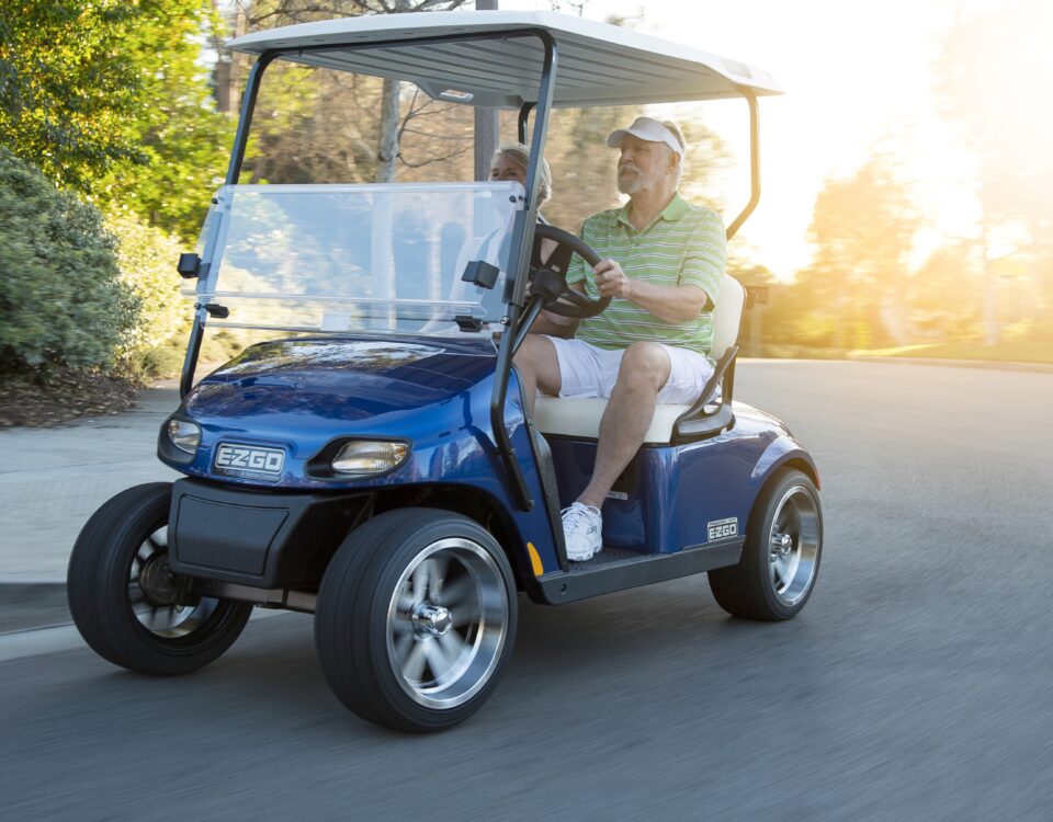 Senior couple riding cart in road.
