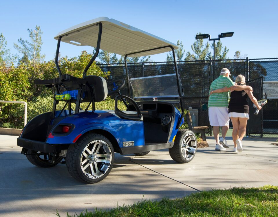Senior couple leaving parked golf cart to play tennis.