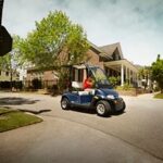 Man driving golf cart through neighborhood.