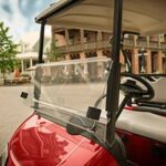 Red golf cart parking on the side of the street.