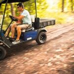 Man driving golf cart in woods.