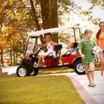 Kids walking away from red golf cart while mom is in the driver’s seat.