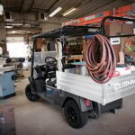 Cushman cart in garage with ladder.