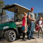 Dad and kids getting off golf cart and getting ready to play sports.