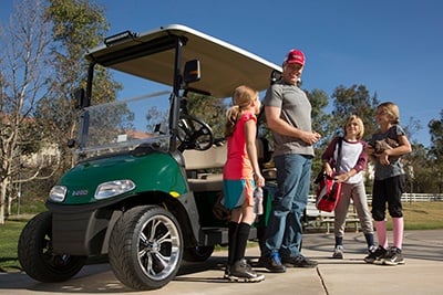 Dad and kids getting off golf cart and getting ready to play sports.