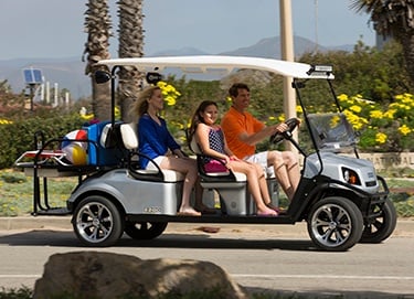 Family riding golf cart to the beach.