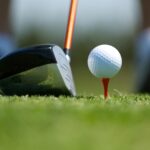 close up photo of a golf club and golf ball on a tee