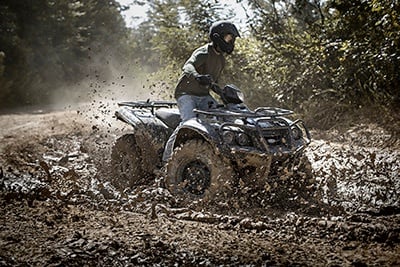 Man driving ATV in mud.