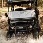 Hunter in golf cart crossing river.