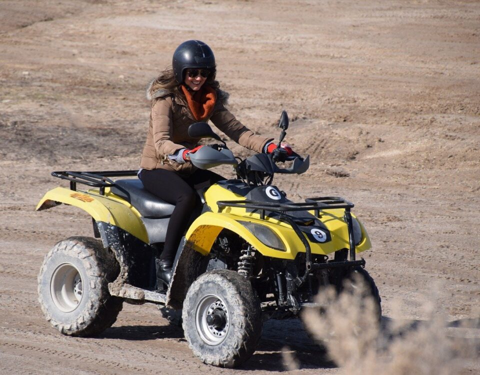 Woman riding ATV in dirt road.