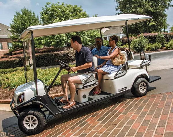 Three people riding E-Z-GO golf cart Shuttle 6.