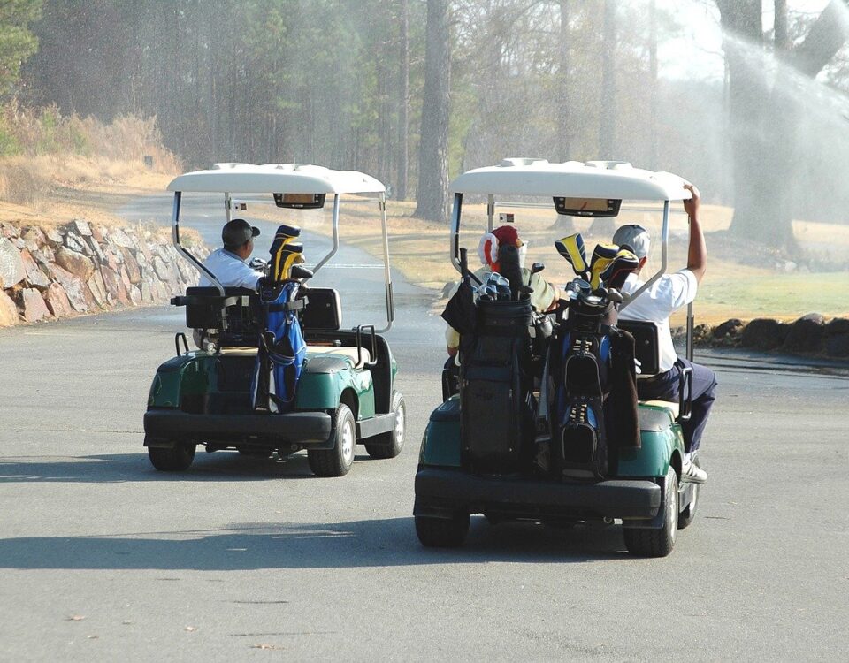 Two men riding golf cart along course.