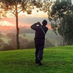 Man golfing with sunset in the back.