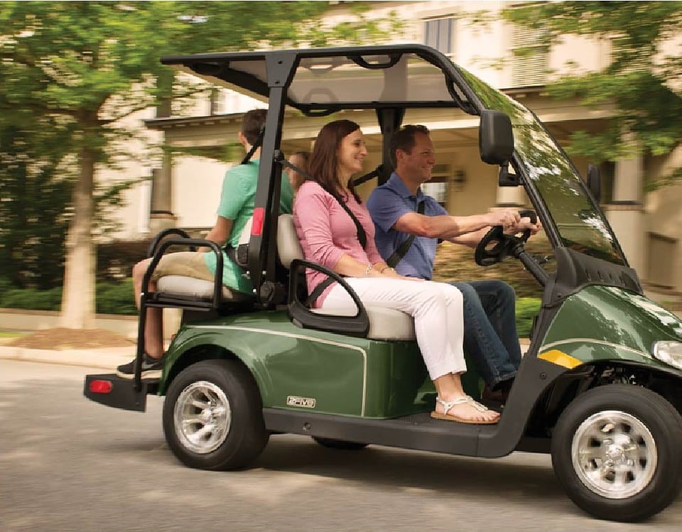 Family riding golf cart in neighborhood.