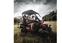 Couple driving red golf cart in open field.
