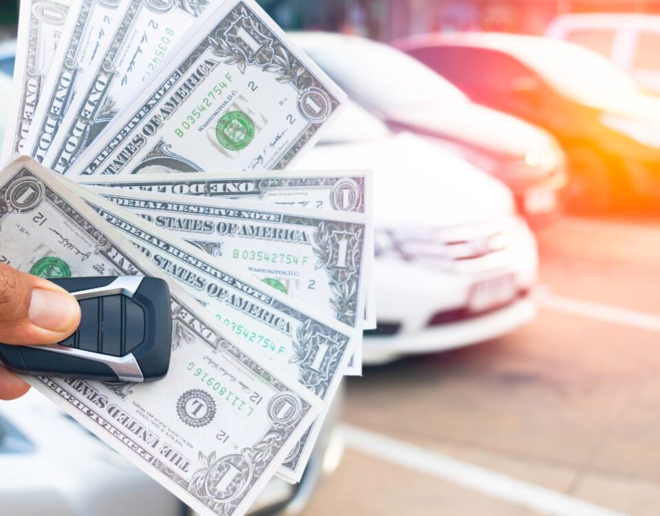 A man's hand holding dollar bills and car keys