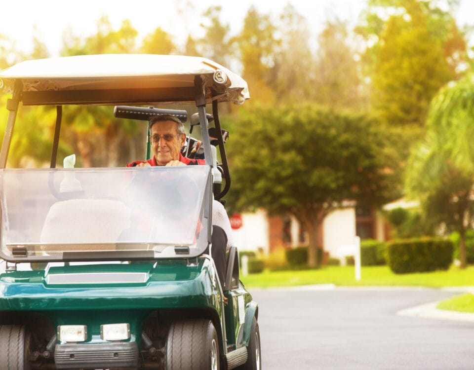 A retired man driving a golf cart in his neighborhood